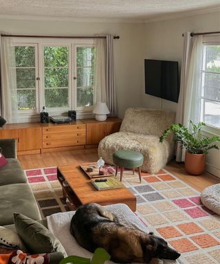 A picture of a small living room with a colorful rug, coffee table, and fluffy chair