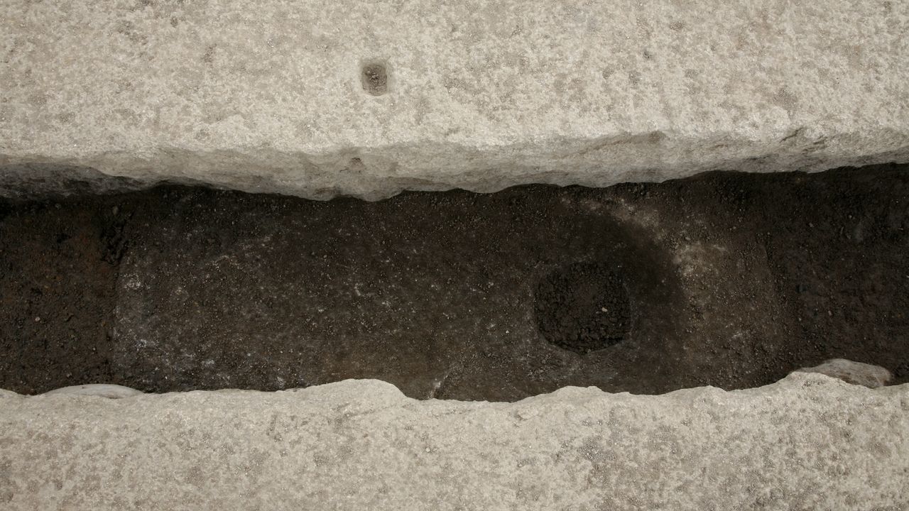 a close-up of the hole in the ground of an ancient toilet