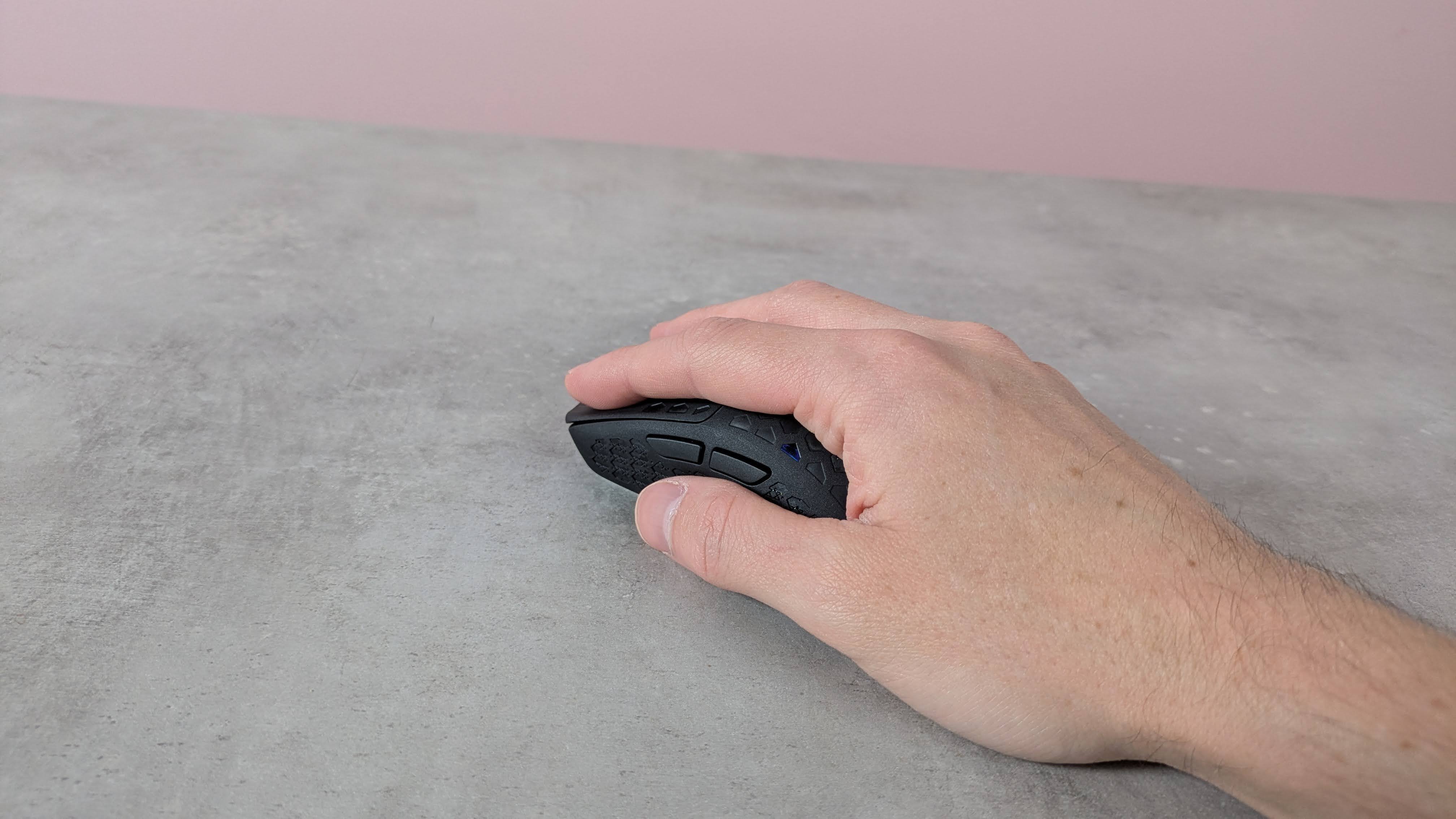 Hand on Keychron G5, on a desk with pink wall in background