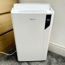 The white Pro Breeze 20L Premium Dehumidifier with Special Laundry Mode being reviewed in a bedroom with a grey carpet
