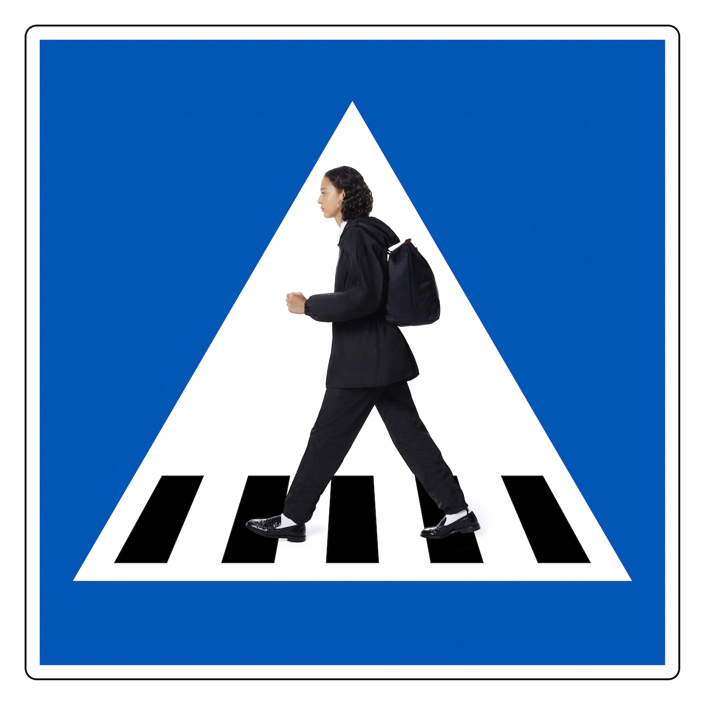 Woman crossing pedestrian zebra crossing in navy poncho and trousers by Longchamp