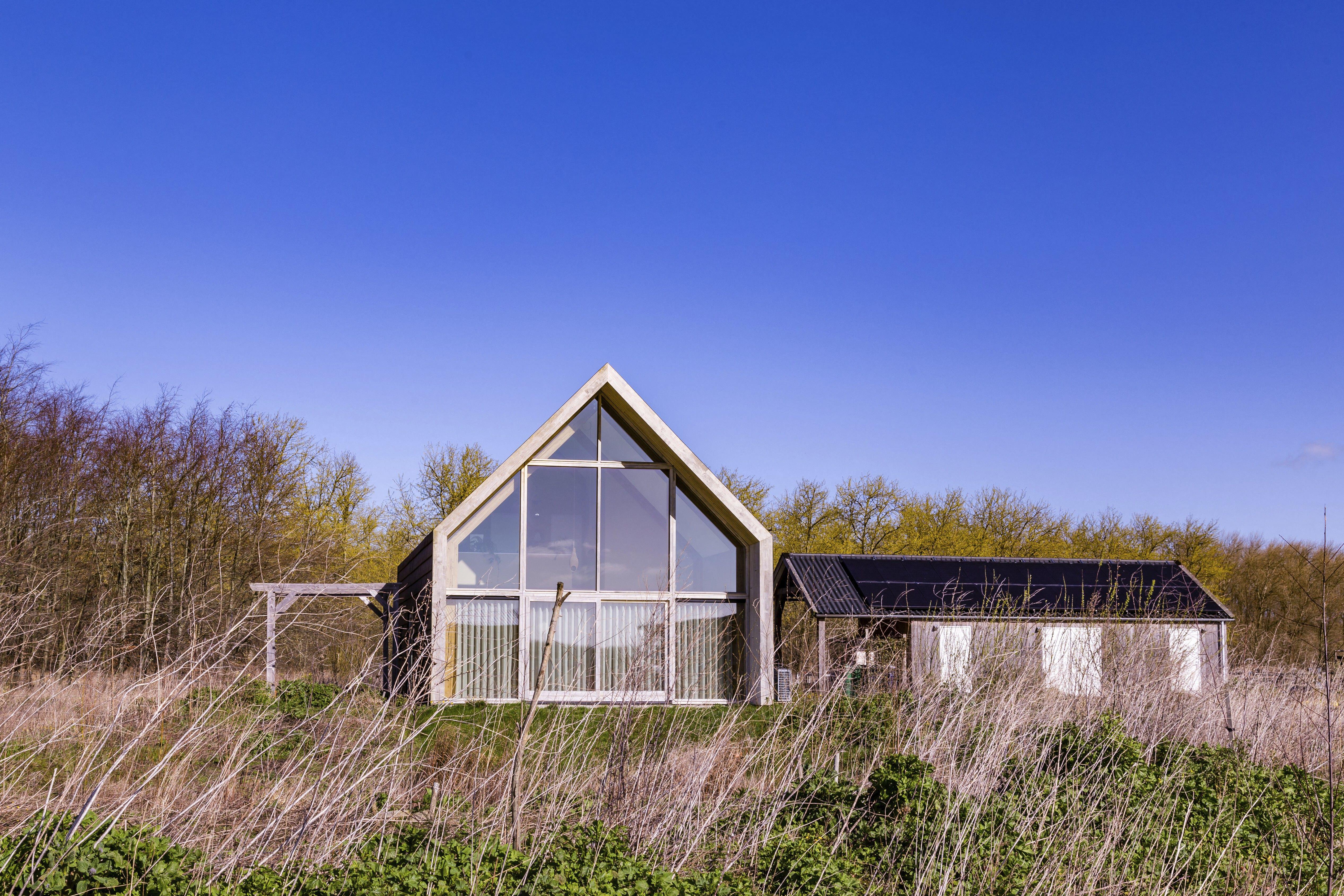 Wooden Eco friendly tiny house in experimental new destrict Oosterwold in Almere. lots of big glass windows and solar panels.