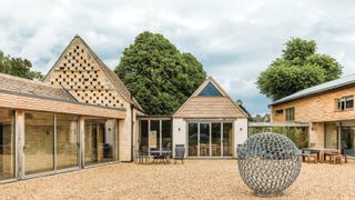 large barn renovation and extensions with gravelled courtyard and large metal sphere sculpture 