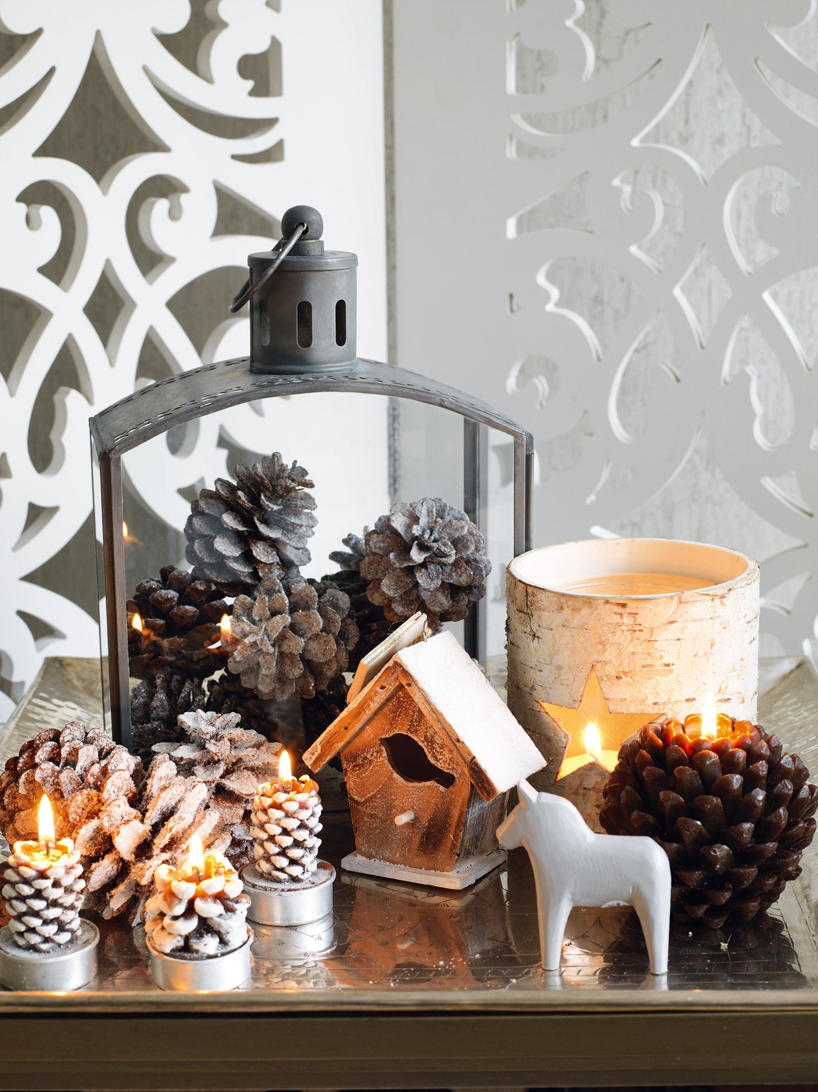 Lantern filled with frosted pinecones, displayed with candles