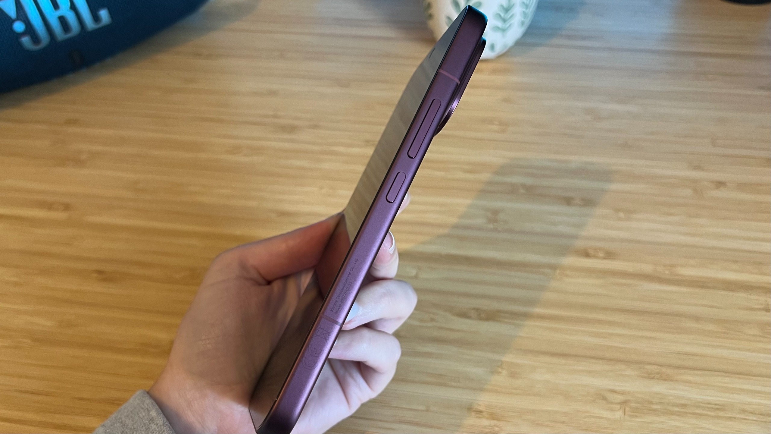 Hand holding Poco F9 Ultra so that its flat side and thickness is visible