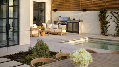 beautiful garden with an outdoor kitchen, dining area, lounge, and a retractable, sinking swimming pool