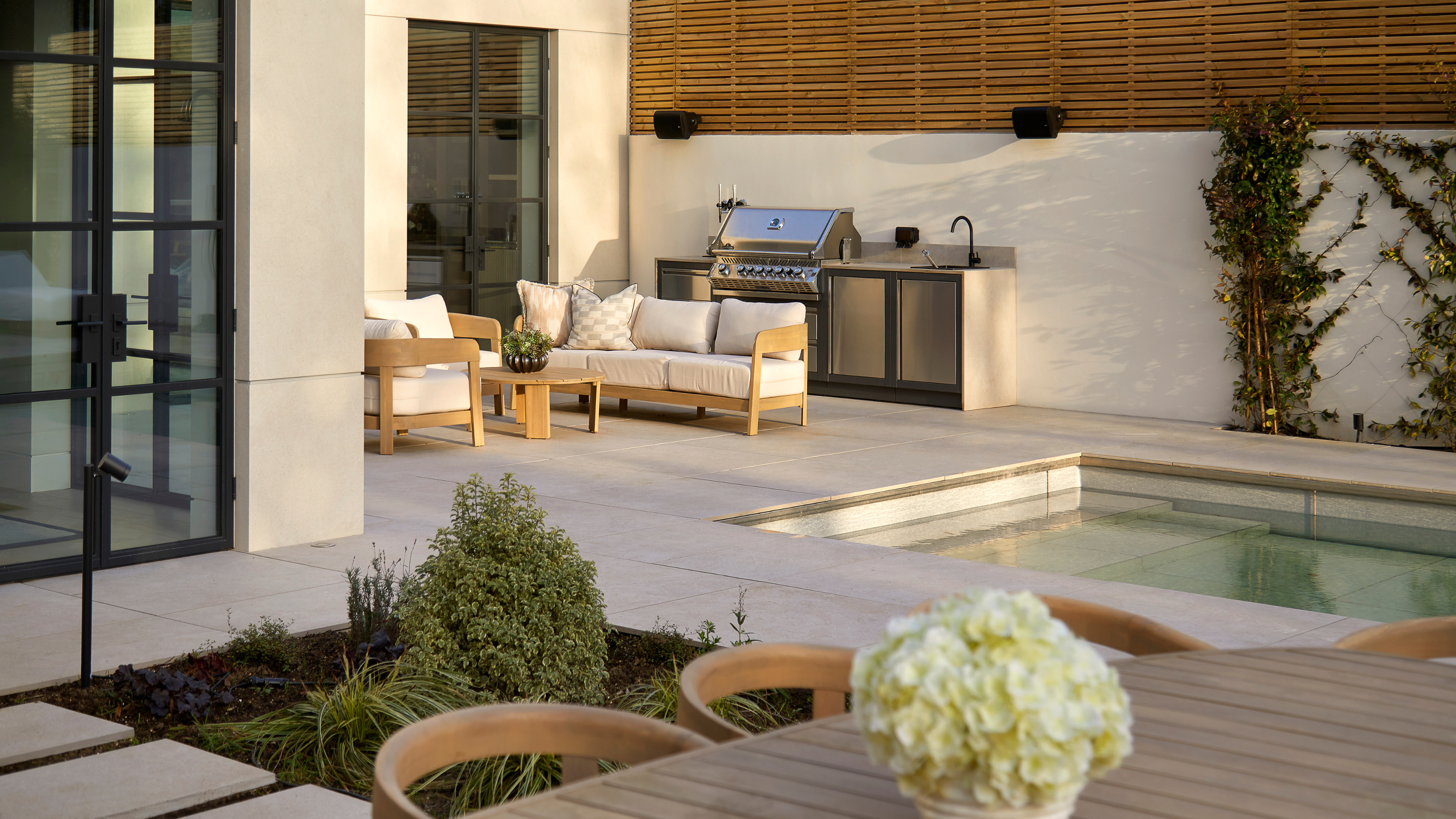 beautiful garden with an outdoor kitchen, dining area, lounge, and a retractable, sinking swimming pool