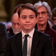 Prince George looks pensive at a Christmas carol concert while wearing a suit and his grandmother, Princess Diana, wears a red dress with shoulder pads