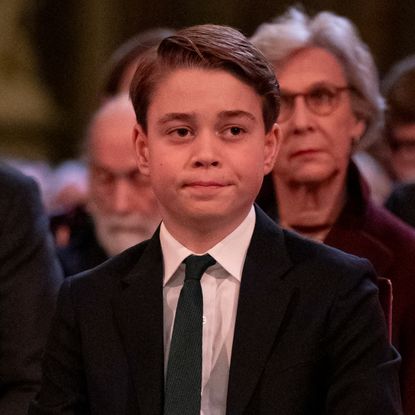 Prince George looks pensive at a Christmas carol concert while wearing a suit and his grandmother, Princess Diana, wears a red dress with shoulder pads