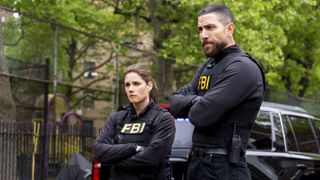 Missy Peregrym as Special Agent Maggie Bell and Zeeko Zaki as Special Agent Omar Adom ‘OA’ Zidan standing outside with FBI vests in FBI season 5