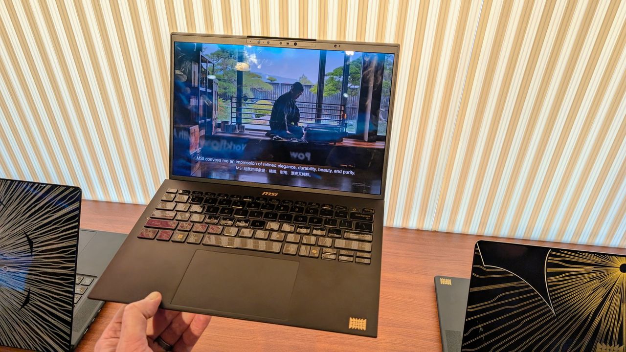 MSI Prestige 13 laptop held in the fingers of one hand