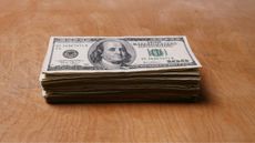 A stack of hundred-dollar bills on a table.