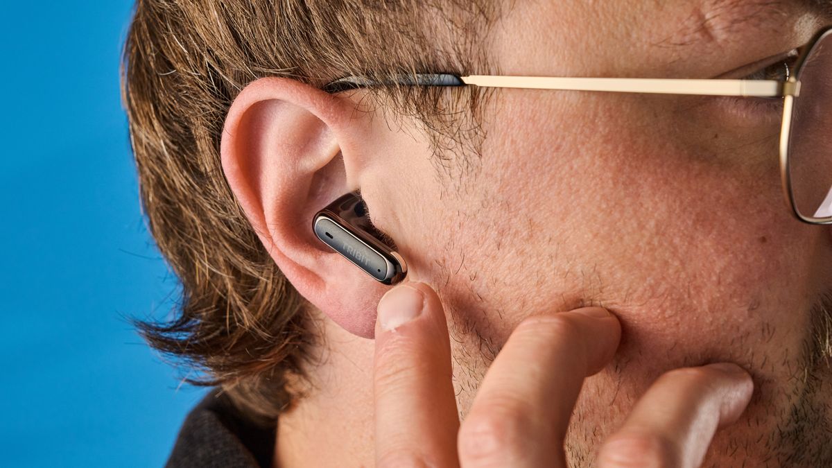 Tribit FlyBuds C3 in black photographed on a blue background with leaves