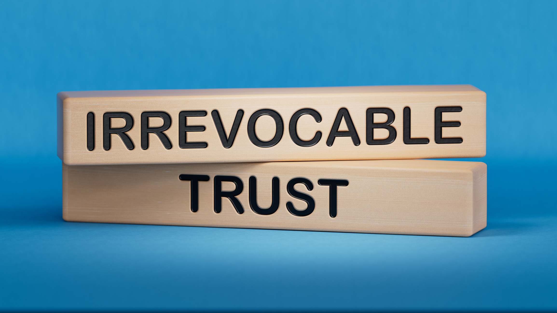 Text IRREVOCABLE TRUST writing in Wooden blocks on blue background.