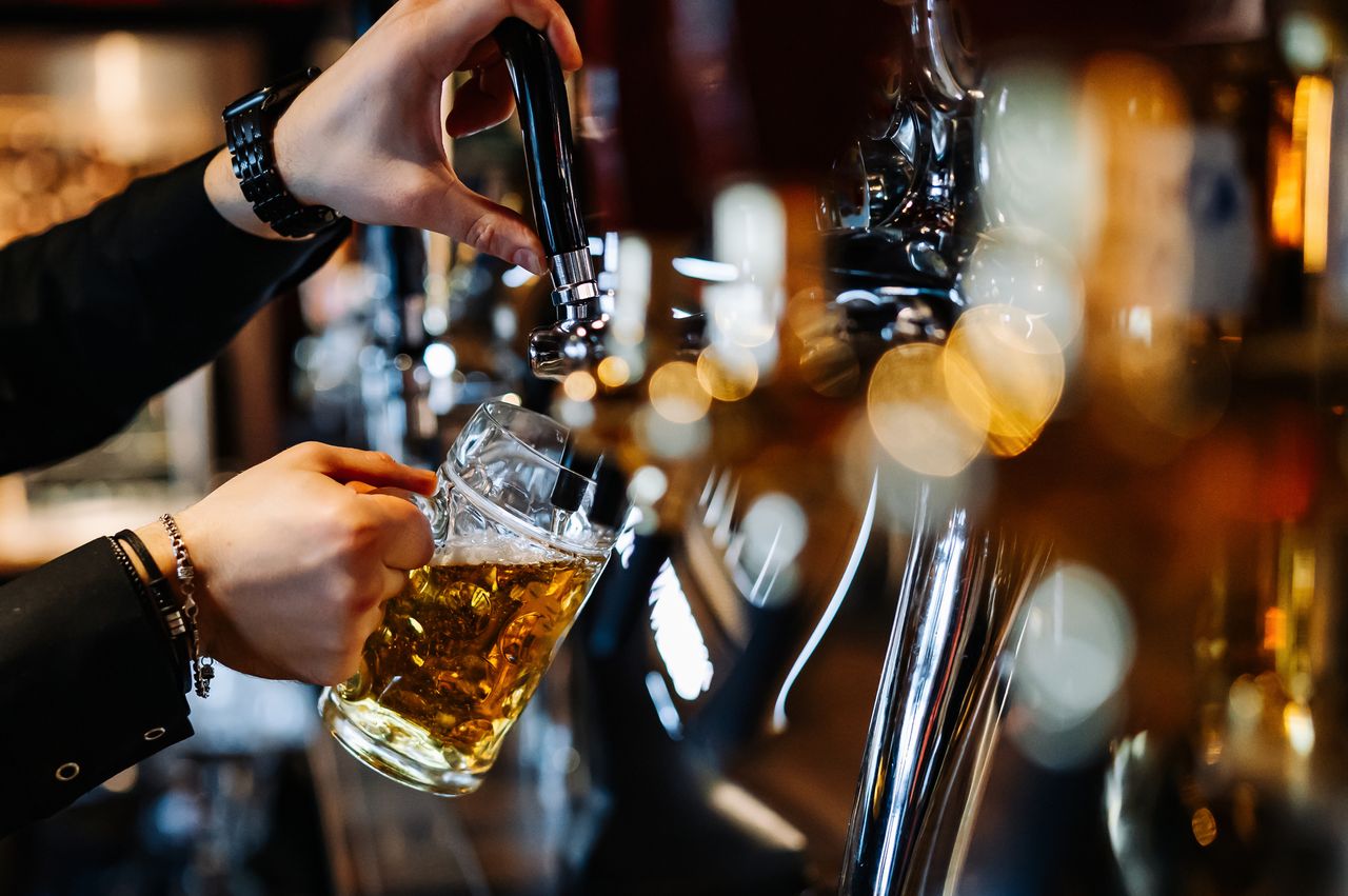 Man bartender hand at beer tap pouring a draught beer in glass serving in a restaurant or pub 