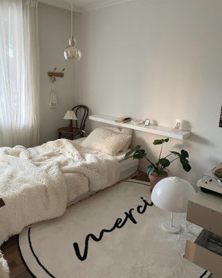 A bedroom with a rug with printed words 'merci'