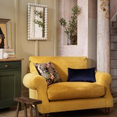 Marks and Spencer yellow armchair with decorative cushions in living room