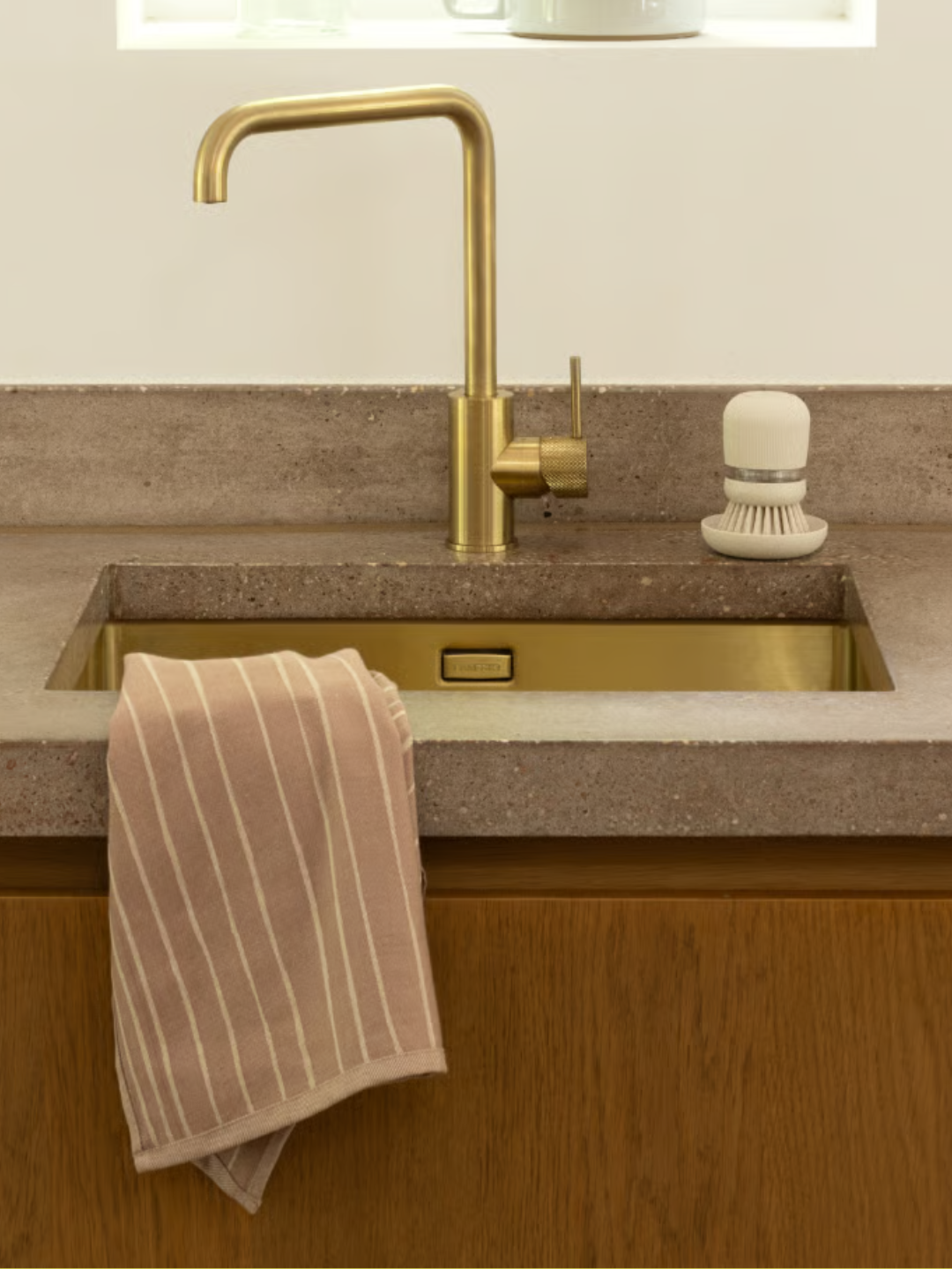 A dish scrubber with soap by a stone sink counter