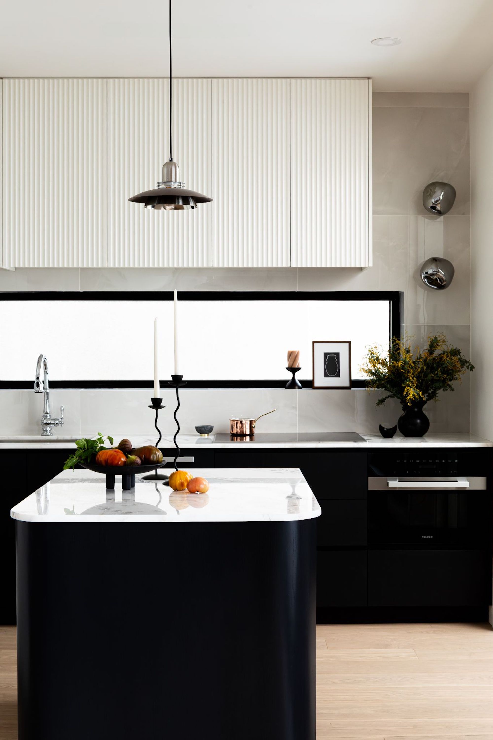 A view of the kitchen space showing the storage above the hob area, and the long black window fitted above the sink and cooker, bringing light into the space.