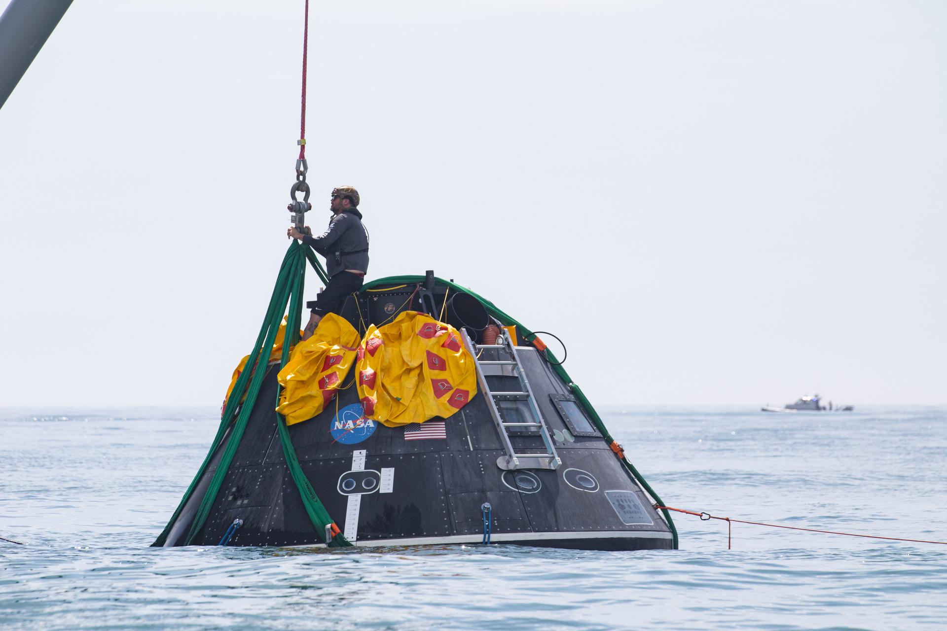 A man stands on a metal dome in the middle of a sea.