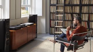 A man siting in a chair in front of the Radia music streamer and amplifier.