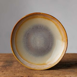 Arhaus Canyon Appetizer Plate on a wooden surface against a light gray wall.