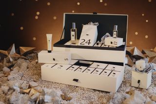 Jo Malone advent calendar 2021 on a table open with some contents visible. It's on a table surrounded by stars and glitter