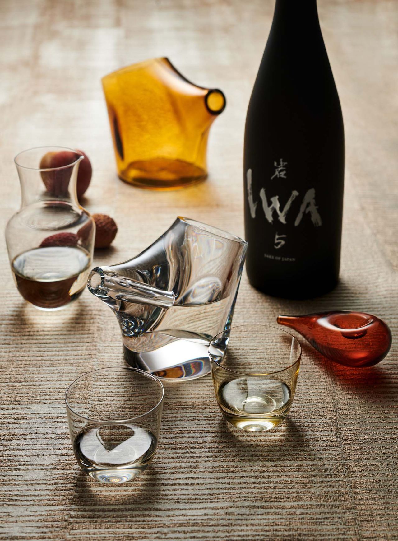 Glassware sake set and other vessels on table with bottle of sake