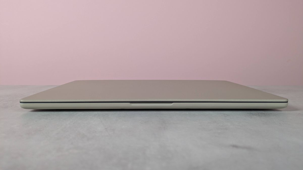 Front view of Asus Zenbook A14, closed on a desk with pink wall in background