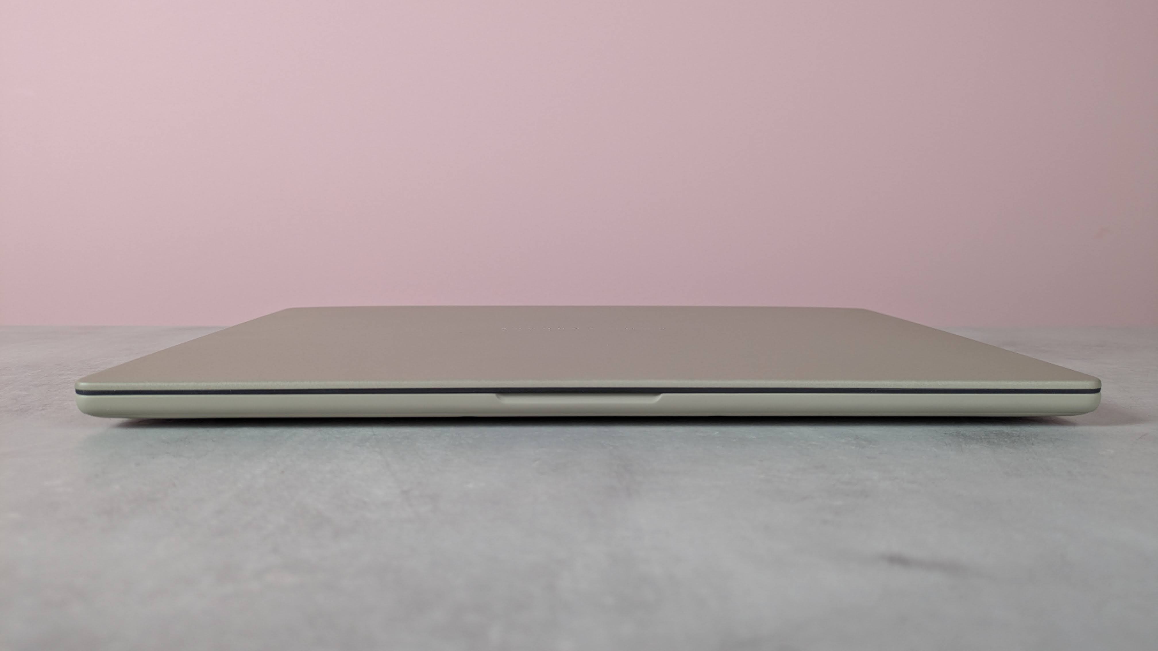 Front view of Asus Zenbook A14, closed on a desk with pink wall in background