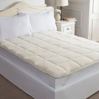Quilted white mattress topper on bed