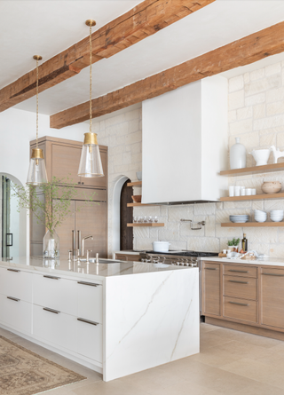 White island with wood kitchen cabinets, hanging pendant lights and exposed beams