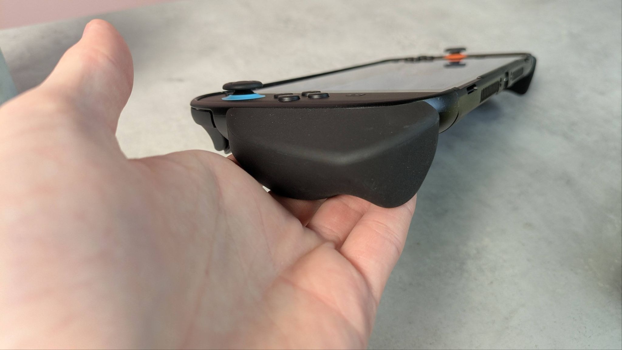 side view of grip of Genki Attack Vector attached to Switch 2, held by fingers