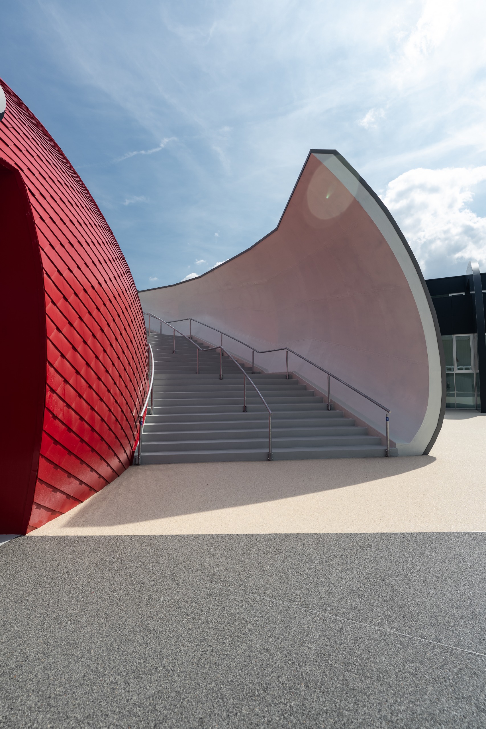 Architectural view of outside stairs and curving red exterior at Moto Guzzi museum and HQ at Mandello del Lario