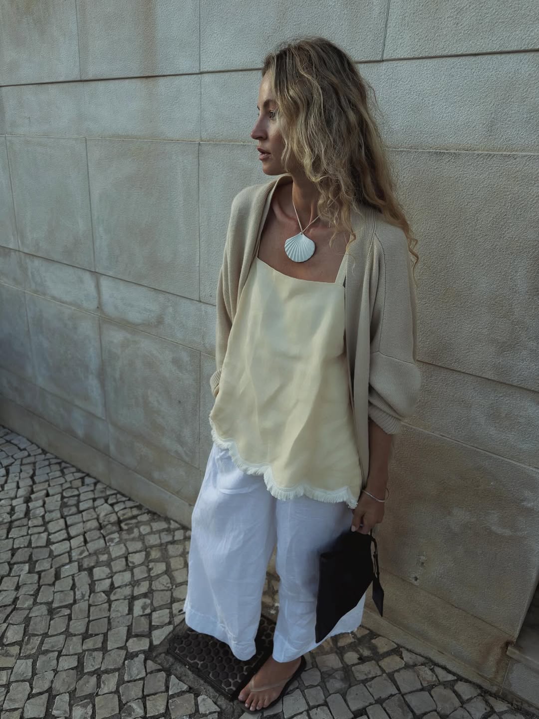 Anouk in beige cardigan, yellow top and white linen trousers