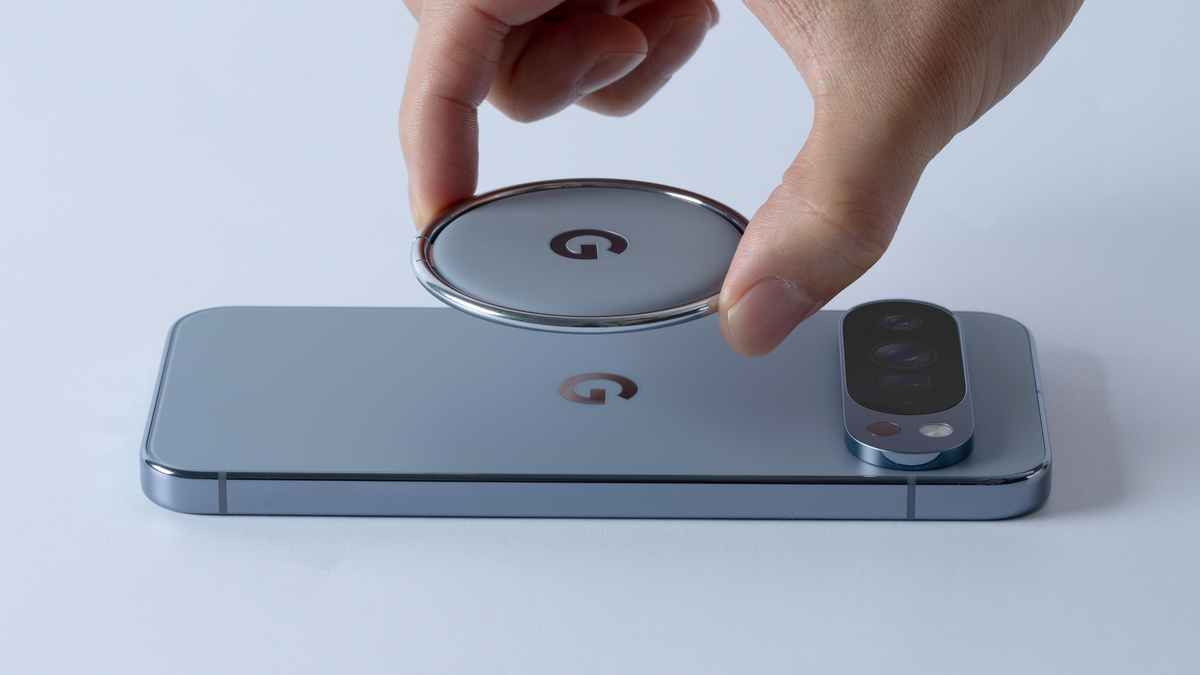 A hand attaching a magnetic ring stand to a Google Pixel 10 phone