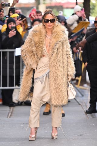 jennifer lopez wearing jumpsuit, fur coat, and heels