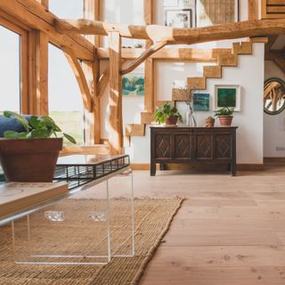 living room wood floor ideas, barn farmhouse style living room with beams, wide floor boards, Perspex coffee table, rug, vintage side board, artwork, plants