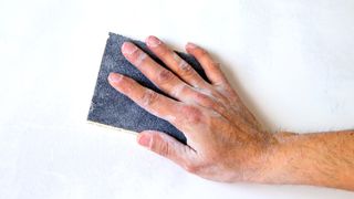 hand with sanding on light coloured wall