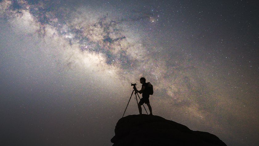 person using a camera on a tripod against the milky way