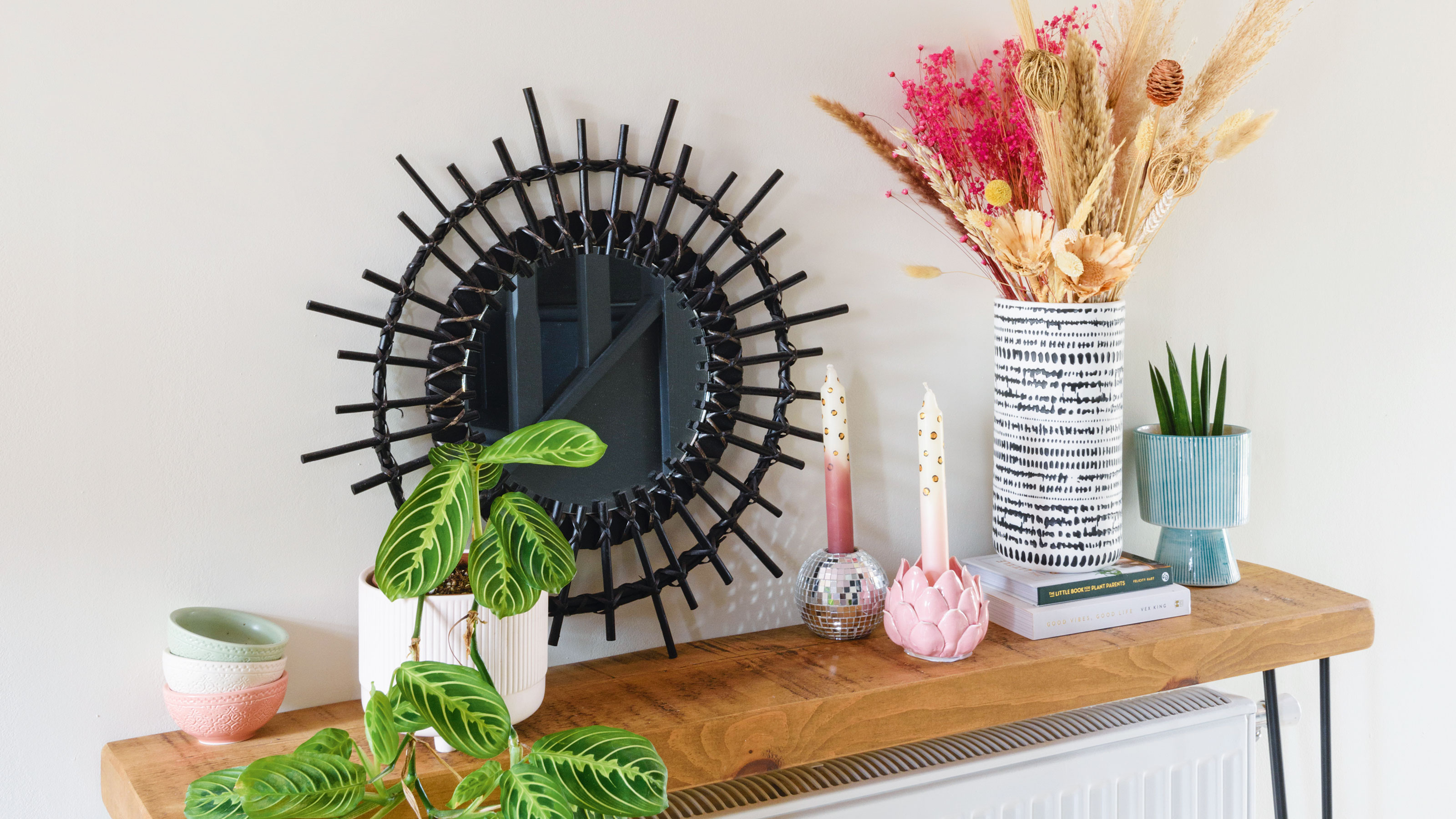 Radiator shelf over a radiator against a white wall decorated with a lamp, vase and candle