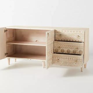 A light wooden side table storage unit with boho patterns drawn on the doors and drawer fronts. The cabinet open