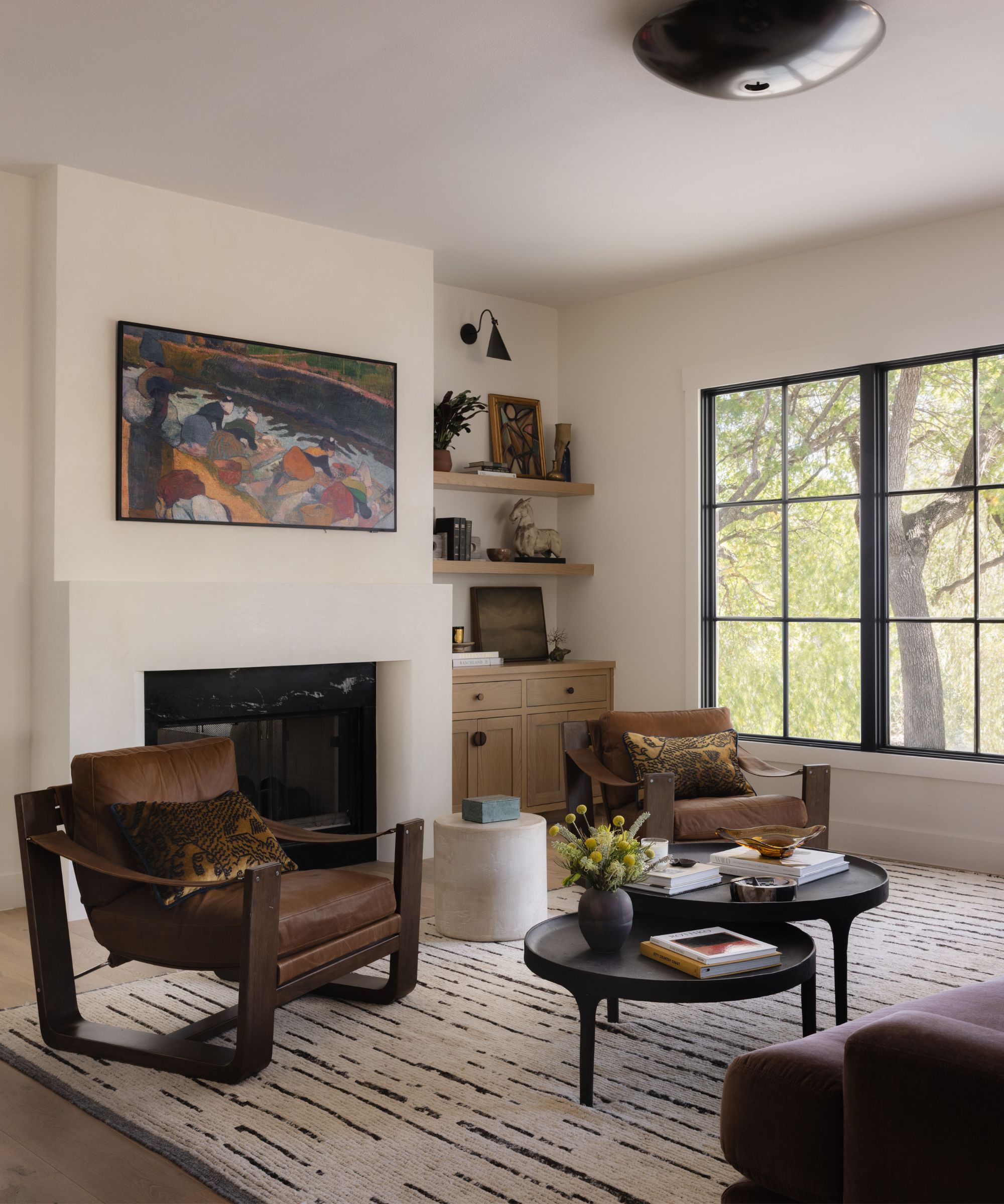 a neutral living room with a large window and an eclectic mix of vintage and mid century furniture