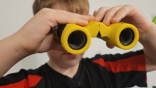 A young boy holding the National Geographic 6x21 children's binoculars