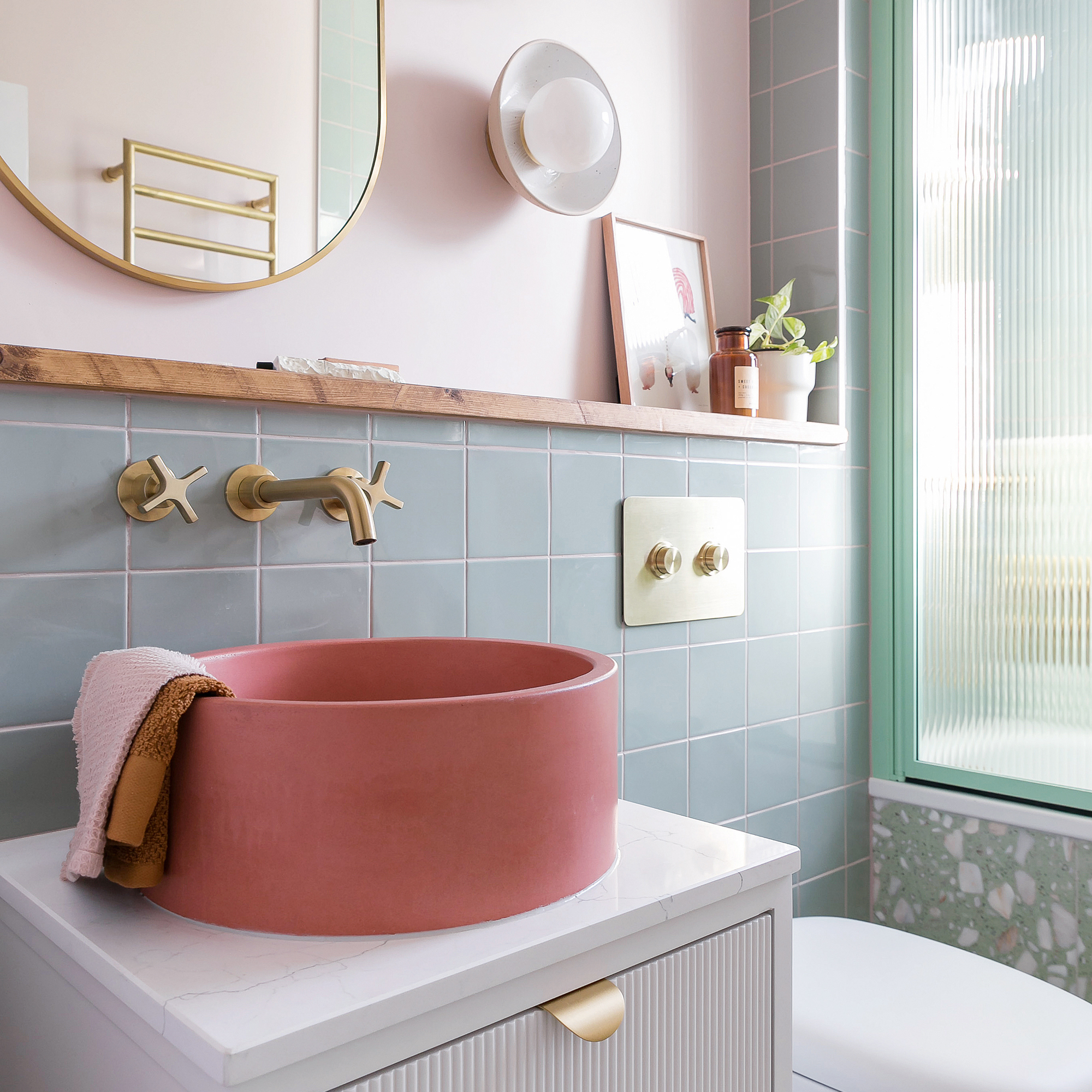a small bathroom with green wall tiles and a bright coral modern bowl basin