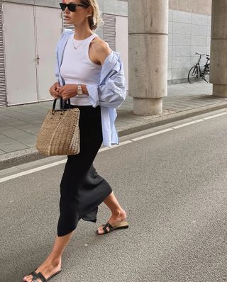 Anouk in a beige sweater vest and black skirt