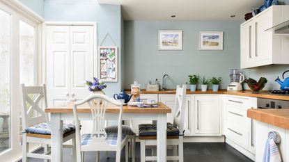 Picture of a large bright kitchen with a light blue and white colour scheme, with dining table and chairs to support a guide on the most unexpected places mould may be hiding