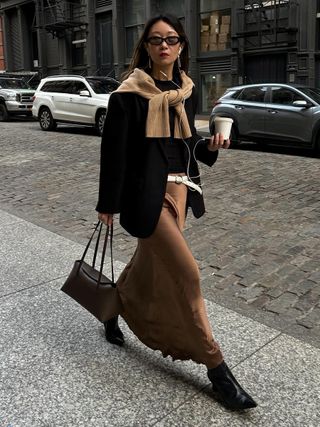 woman wearing brown slip skirt with black ankle boots and black sweater and blazer