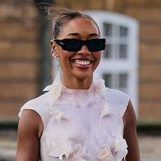 A woman wearing a white textured top and white wide leg pants in Copenhagen