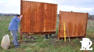 Two people placing fence panel next to another fence panel